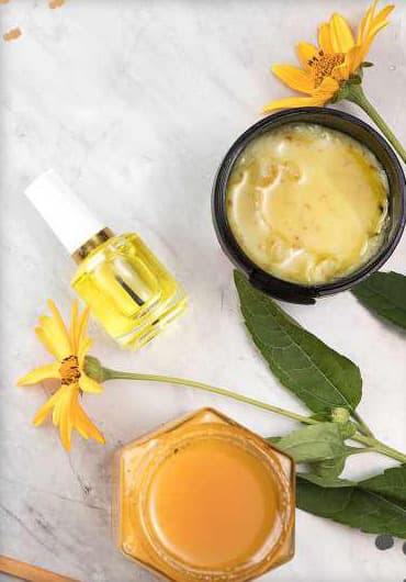 Natural skincare creams and flowers on a marble counter